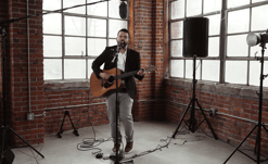 Man playing guitar and singing into microphone